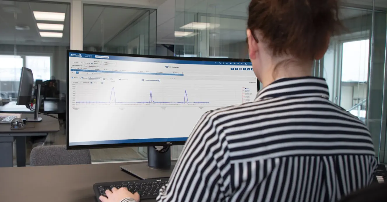 Person monitoring real-time temperature data on a computer screen using a cold chain tracking dashboard in an office setting.