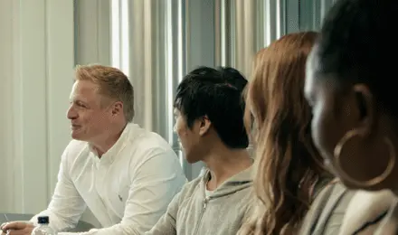 A diverse group of professionals seated together in a meeting, engaged in discussion and collaboration, representing teamwork, inclusion, and shared decision-making.